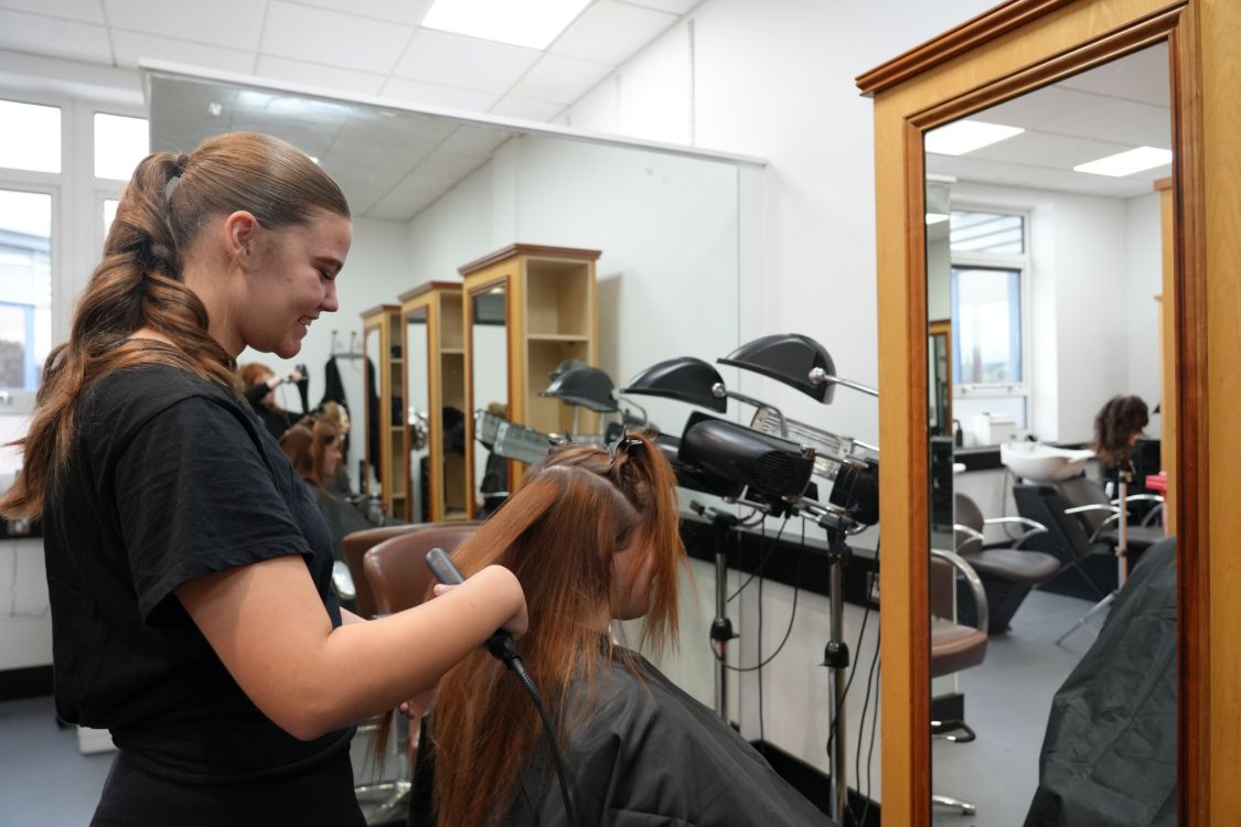 Madison Bell working on a client in front of a mirror in the SERC hair salon in Bangor